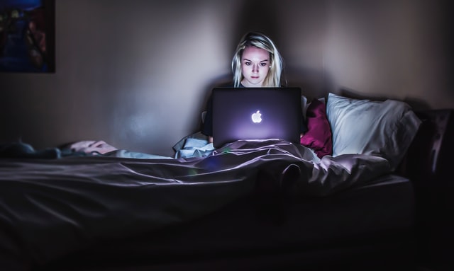 暗い部屋でパソコン画面を見ている女性